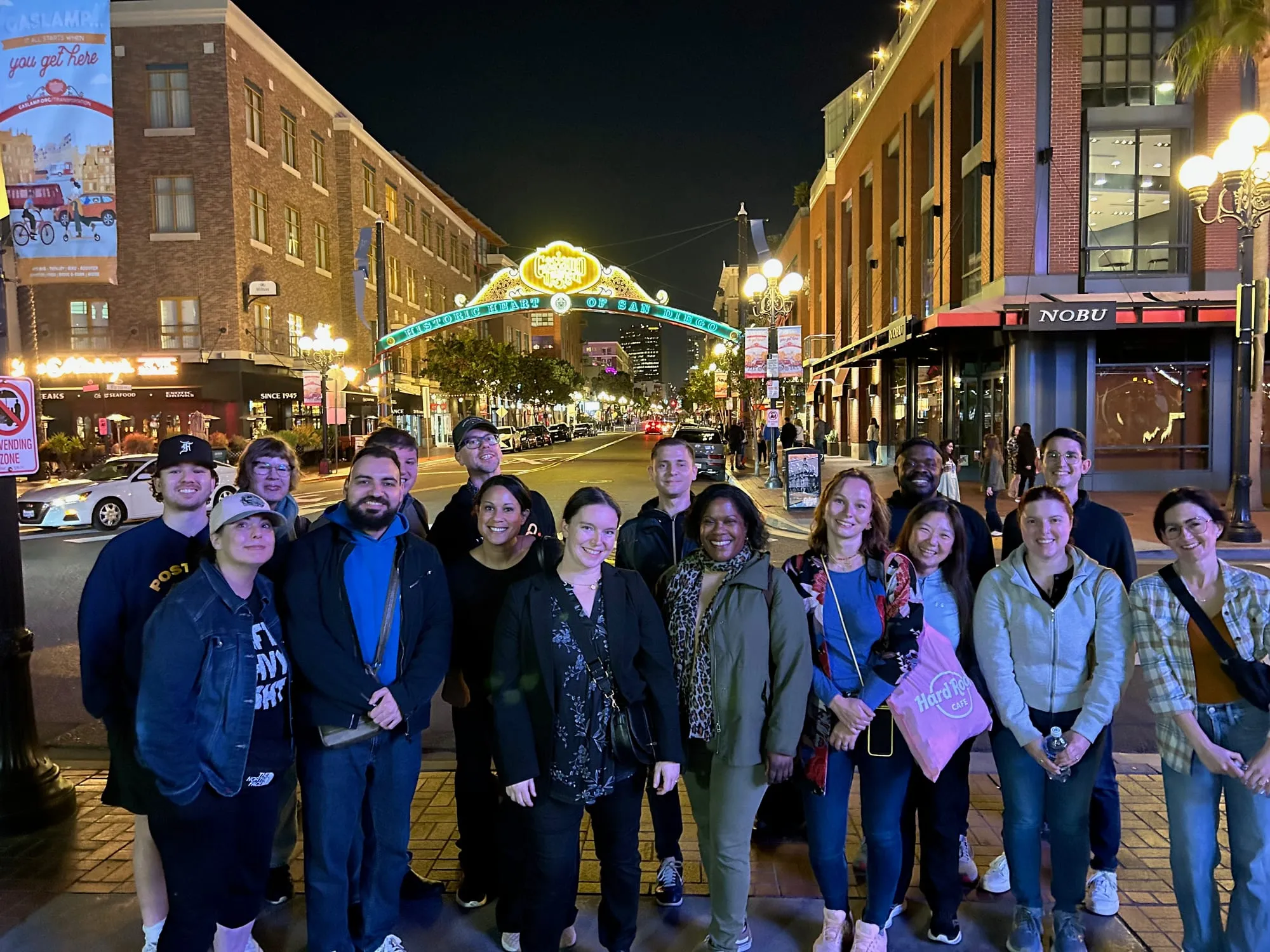 Group photo of conference attendees under the Gaslamp Quarter sign at night