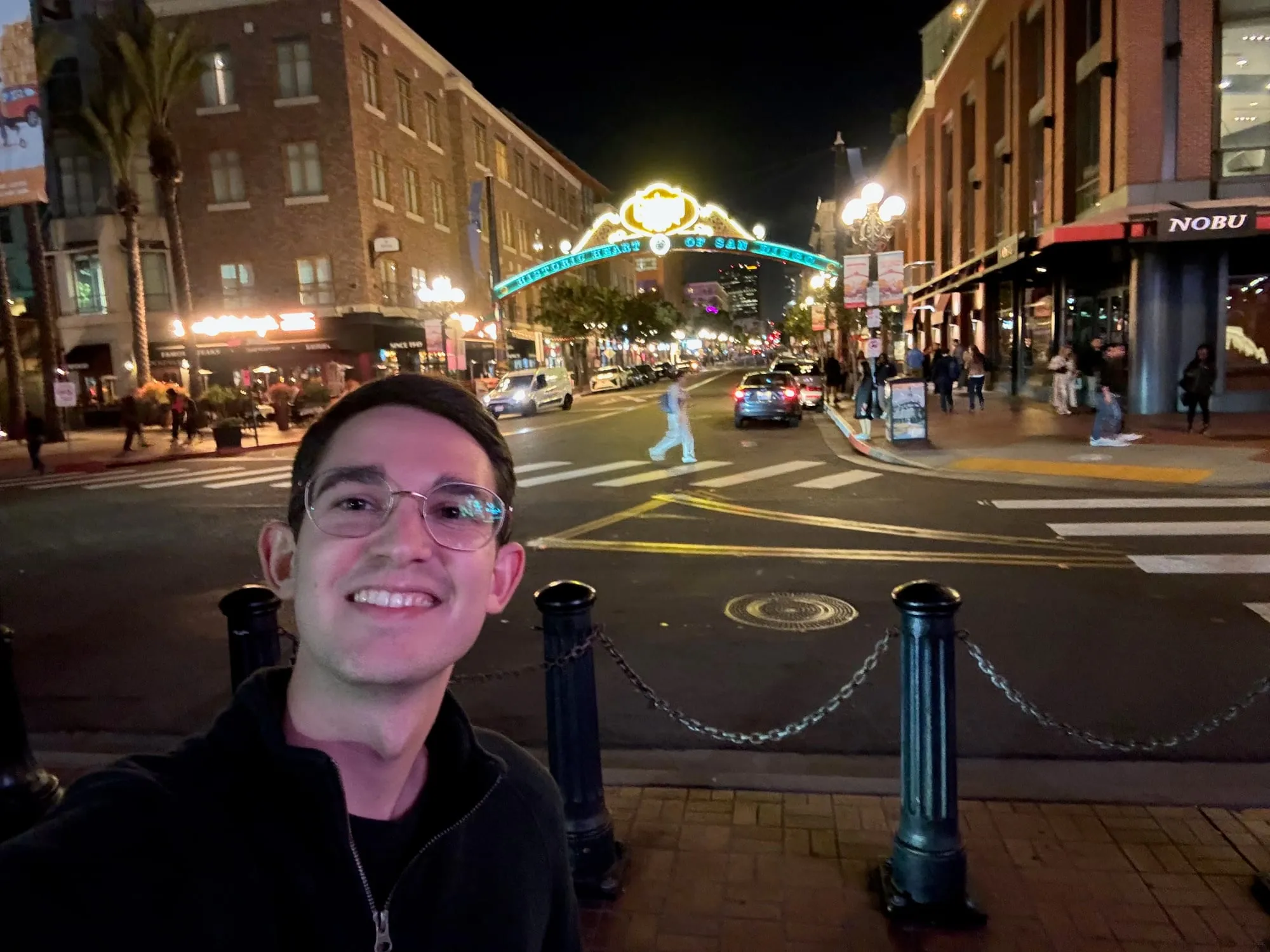 Zach smiling in front of the Gaslamp Quarter sign in San Diego at night